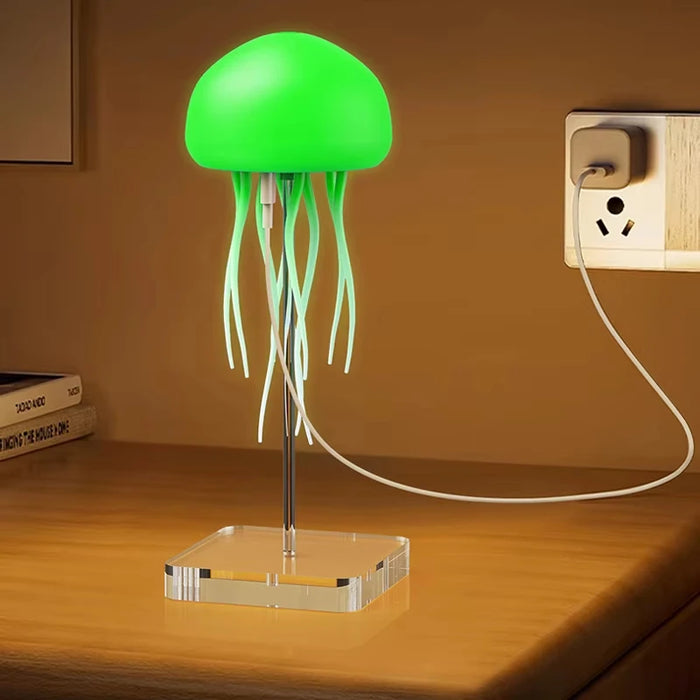 Green jellyfish-shaped lamp on a wooden surface with a wall socket in the background.