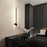 Modern bedroom with a black wall-mounted light fixture, nightstand, and bed.