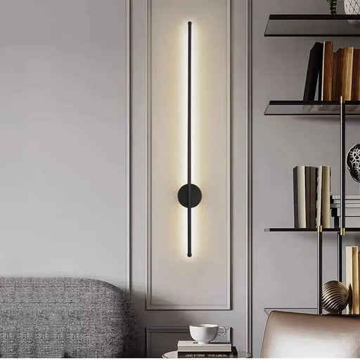 Modern wall sconce in a stylish interior setting with a bookshelf and sofa.