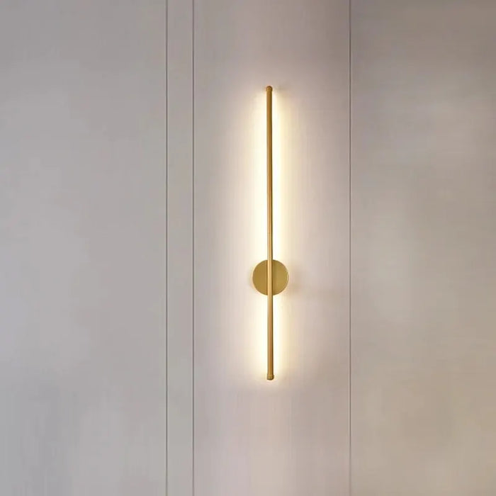 Modern wall lamp with a gold finish on a neutral wall